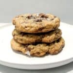 three chocolate chip cookies stacked on a white plate