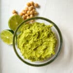 Guacamole in a glass bowl with lime and chickpeas