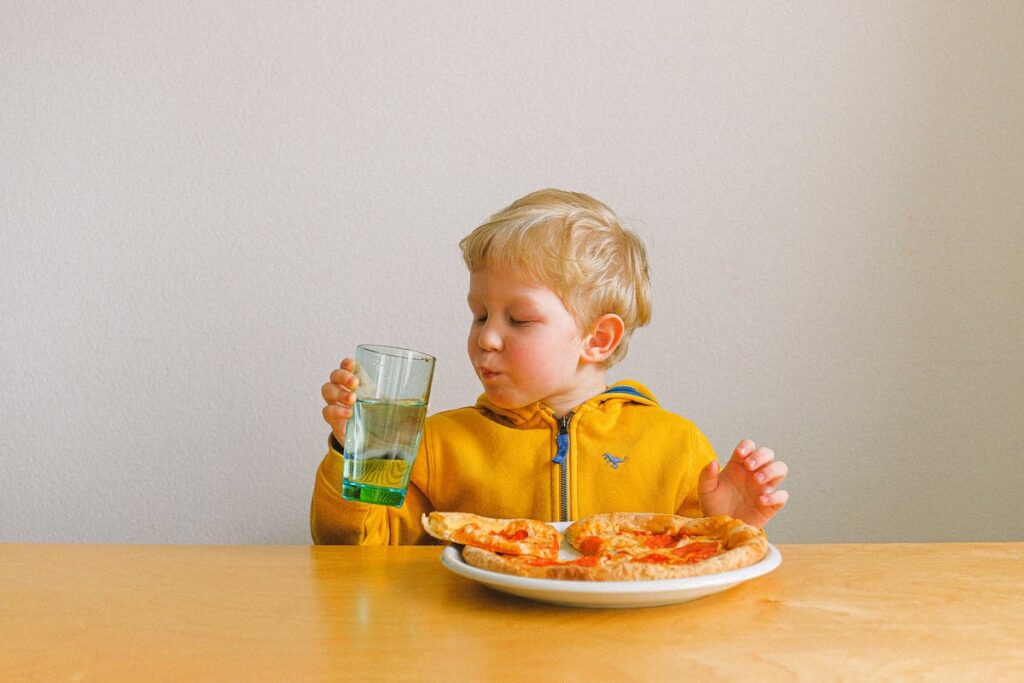 child pocketing food while eating pizza at the table