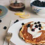 protein pancakes on a table with cream and blueberries