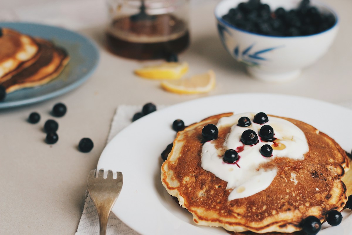 protein pancakes on a table with cream and blueberries